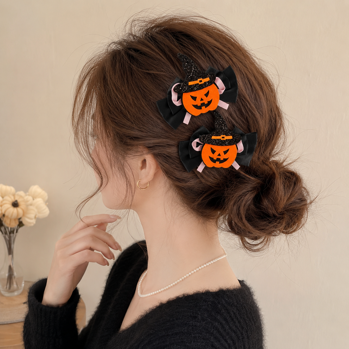 Woman wearing two Halloween pumpkin witch-hat hair clips in a low bun hairstyle.